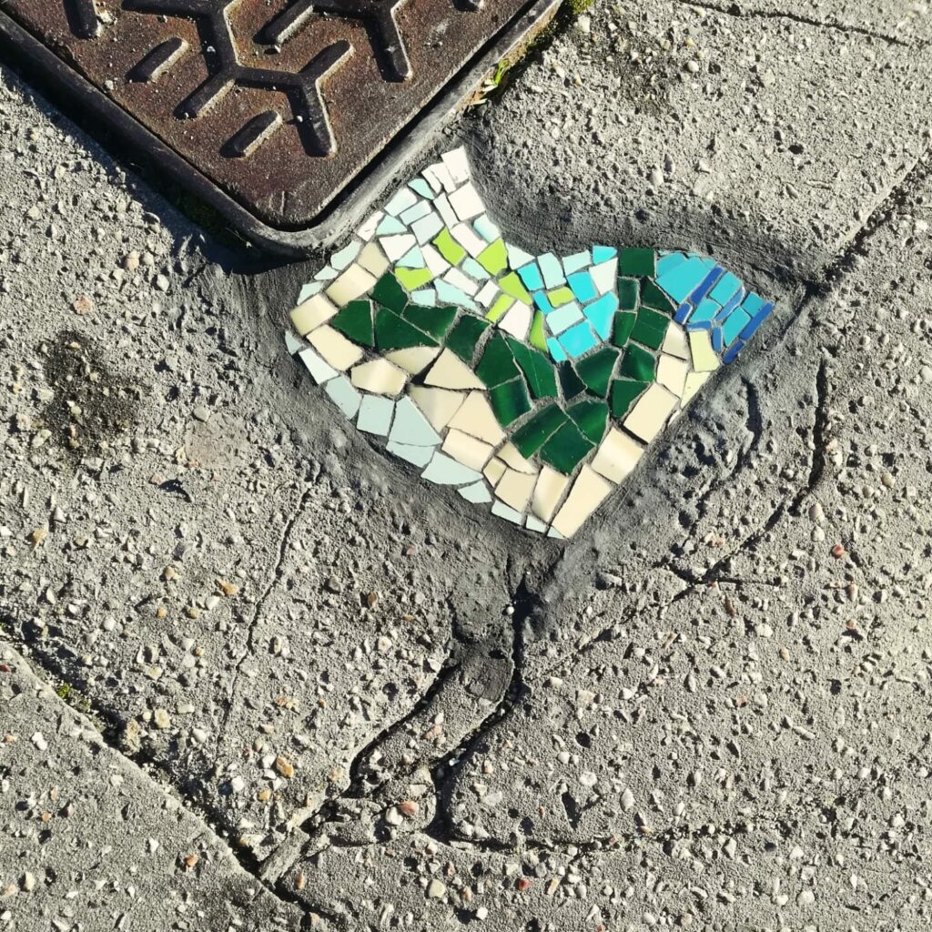 Mosaïque urbaine réalisée à Bayonne, Fresque collective à Emmaüs, Atelier participatif de mosaïque, fresque mosaïque urbaine Bayonne Elzarra, fresques en mosaïque, mosaïque urbaine, créations participatives, art public Pays Basque, Petites mosaïques urbaines réparant le bitume dans l’espace public, une démarche artistique engagée